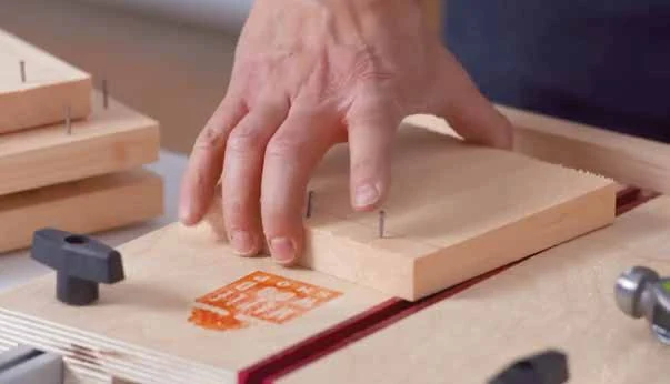 A side board supported on a work surface while nails are started before assembly.